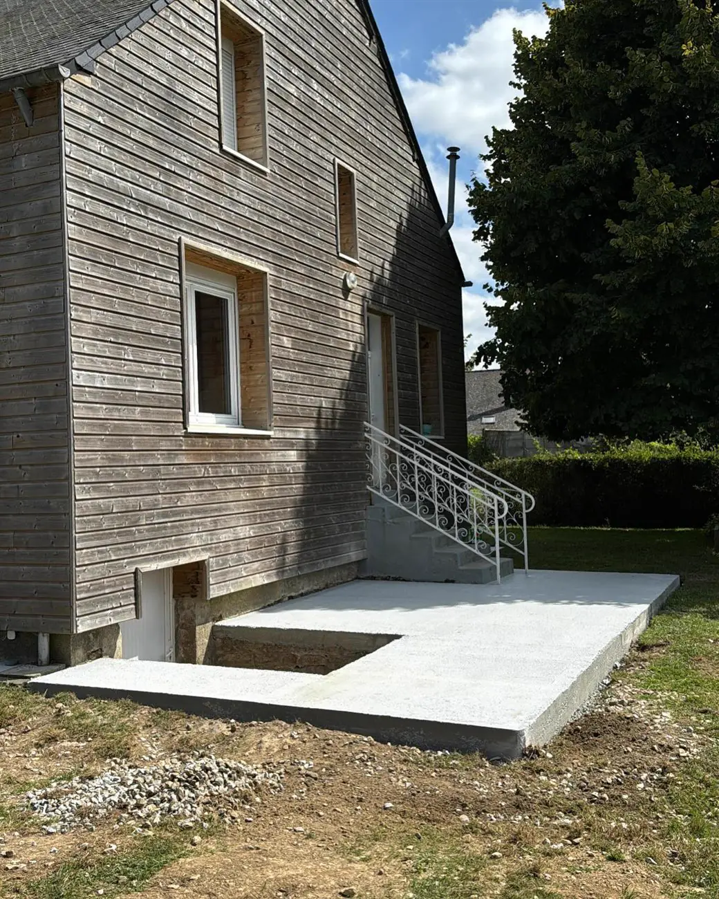 Après : terrasse en béton coulée devant une maison à bardage bois