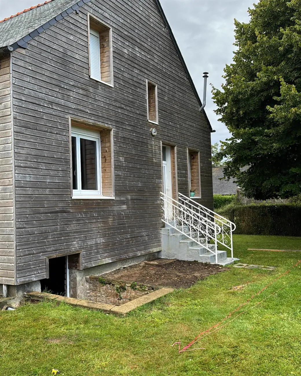 Avant : terrain en terre devant la maison, sans terrasse