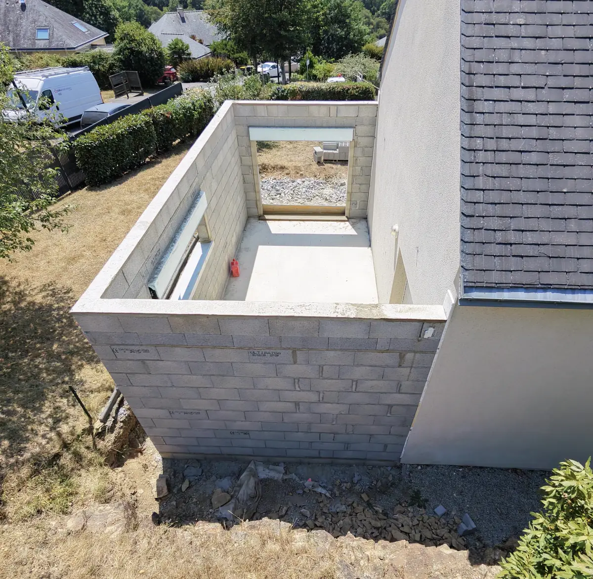 Intérieur d'une extension : dalle coulée et murs en parpaing montés, vue plongeante