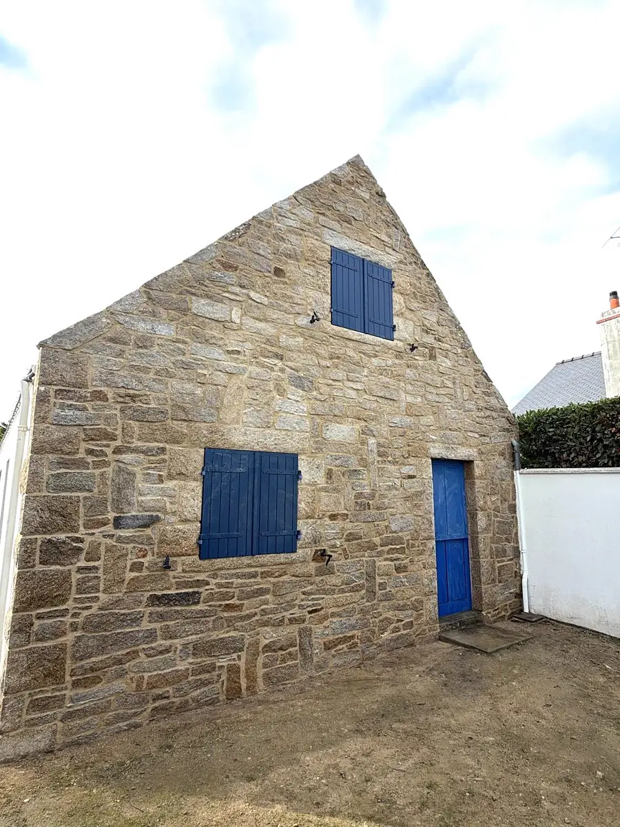 Pignon en pierre aux joints repris, volets et porte bleus, bâti ancien breton