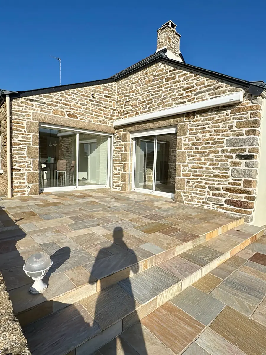 Terrasse en dallage de pierre naturelle devant une façade rejointoyée à la chaux