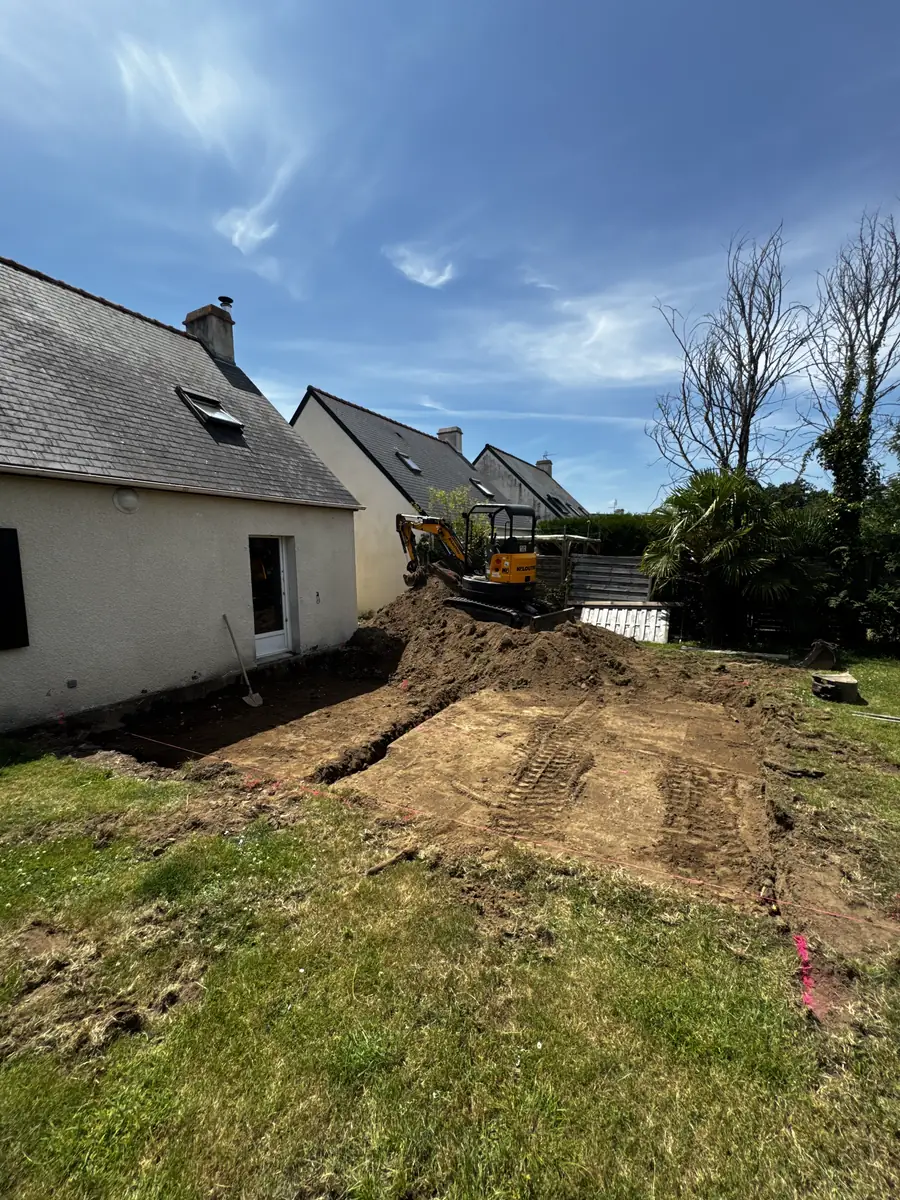 Décaissement du terrain le long du pignon d'une maison bretonne, mini-pelle au fond