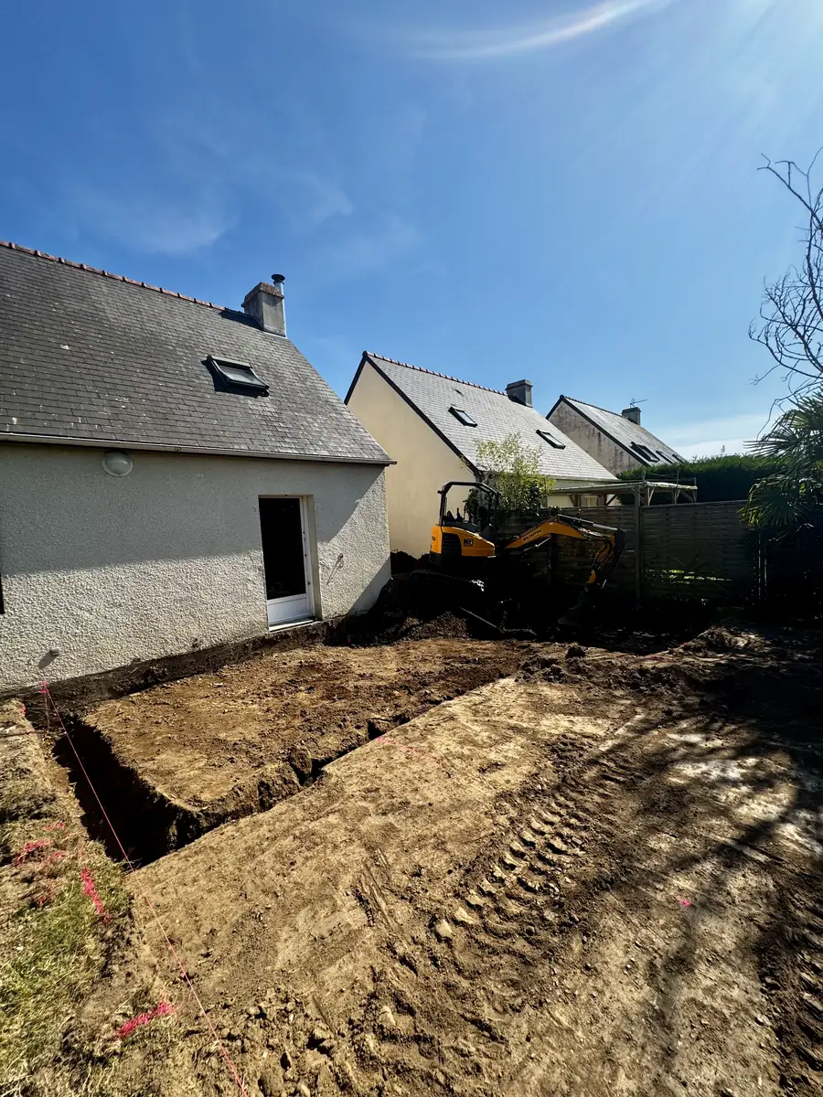 Mini-pelle jaune et tranchées ouvertes sur un chantier de terrassement dans le Morbihan